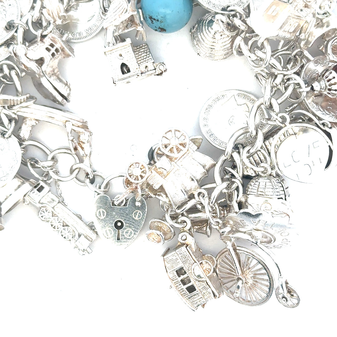 Silver charm bracelet weighing 128.8g with various charms, unbranded jewelry accessory, shown in a close-up image.