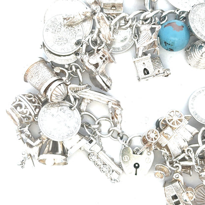 Silver charm bracelet with intricate designs, weighing 128.8g, featuring multiple charms on a durable metal chain.