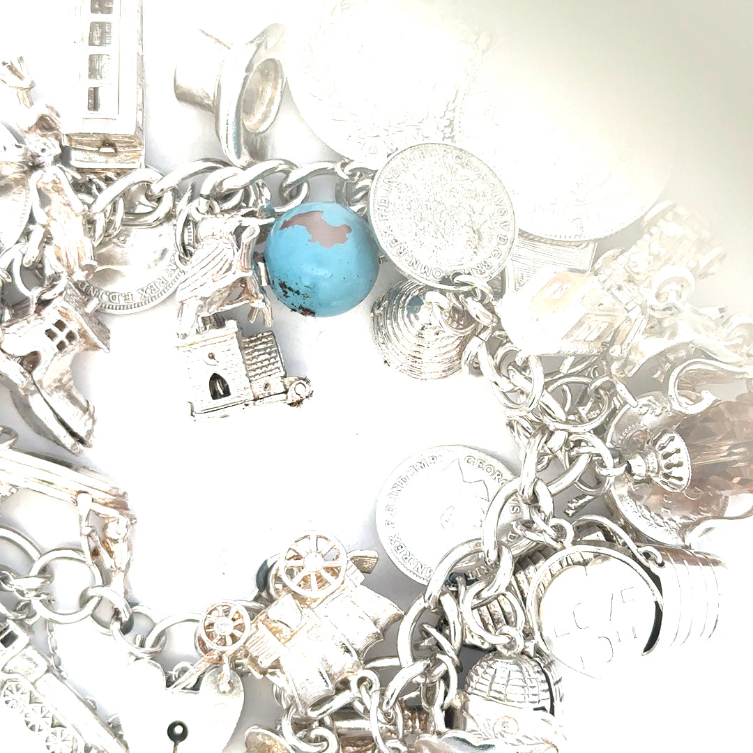 Silver charm bracelet weighing 128.8g, featuring intricate charms and links, unbranded jewelry accessory for stylish wear.