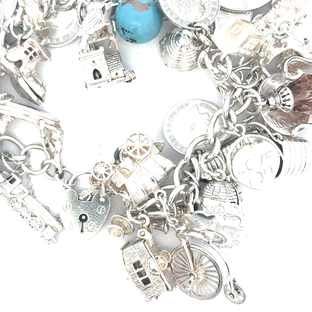 Silver charm bracelet weighing 128.8g, unbranded with decorative charms, displayed on a neutral background.