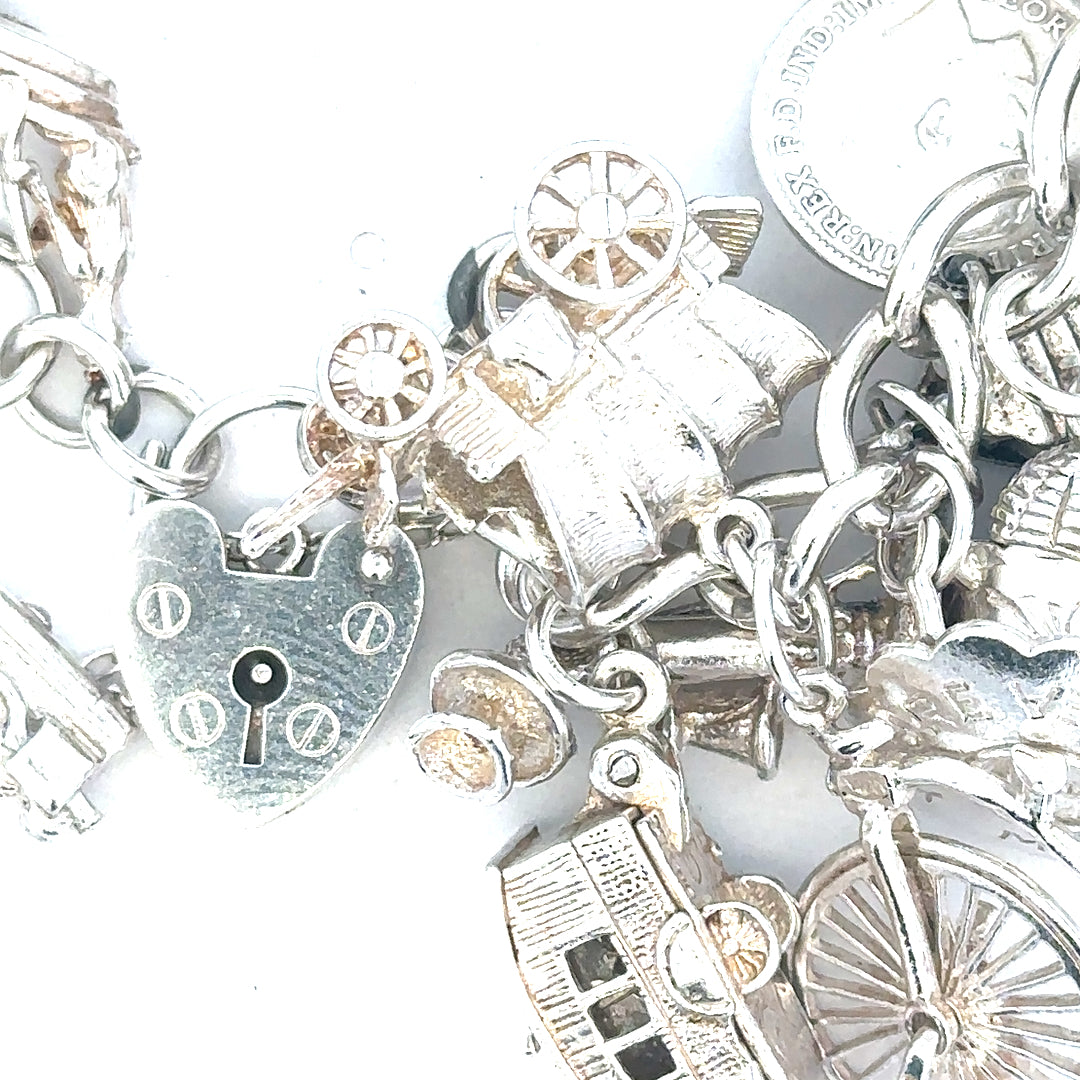 Silver charm bracelet weighing 128.8g with multiple decorative charms, unbranded, displayed on a neutral background.