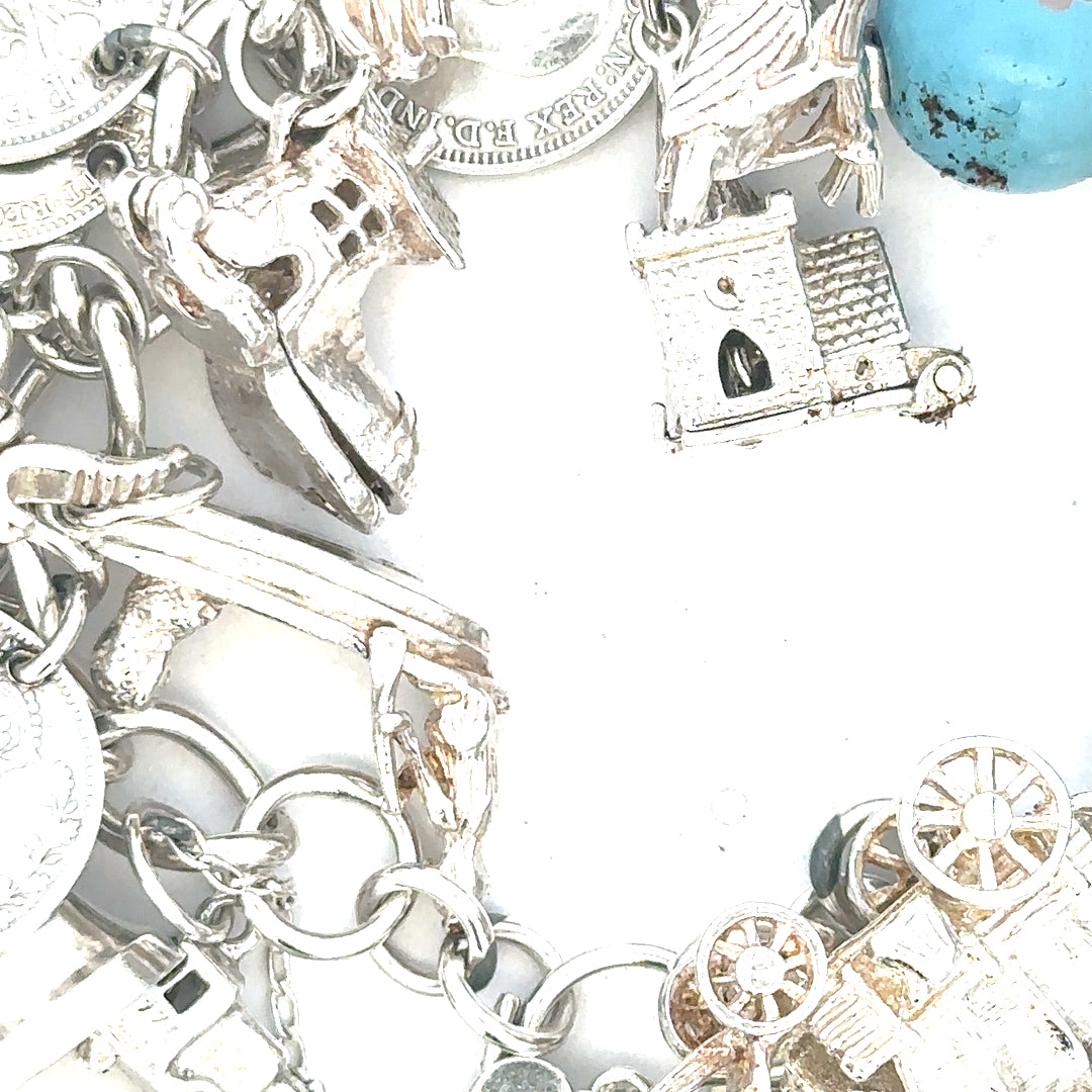 Silver charm bracelet with intricate designs, weighing 128.8g, showcasing detailed charms and a sleek bracelet style.