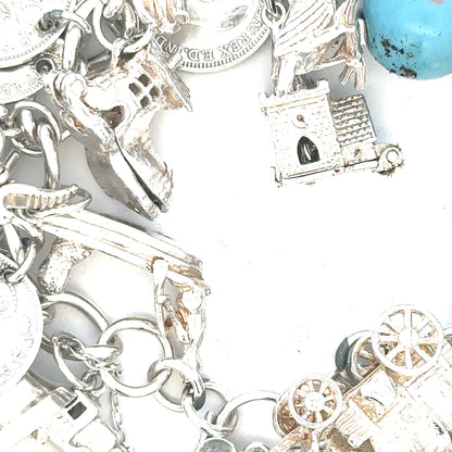 Silver charm bracelet with intricate designs, weighing 128.8g, showcasing detailed charms and a sleek bracelet style.
