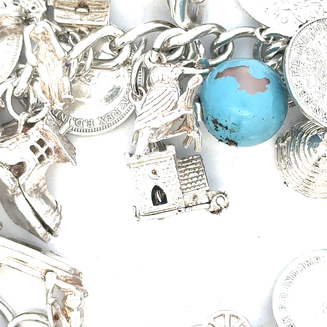 Silver charm bracelet weighing 128.8g with multiple decorative charms, unbranded jewelry accessory for women.