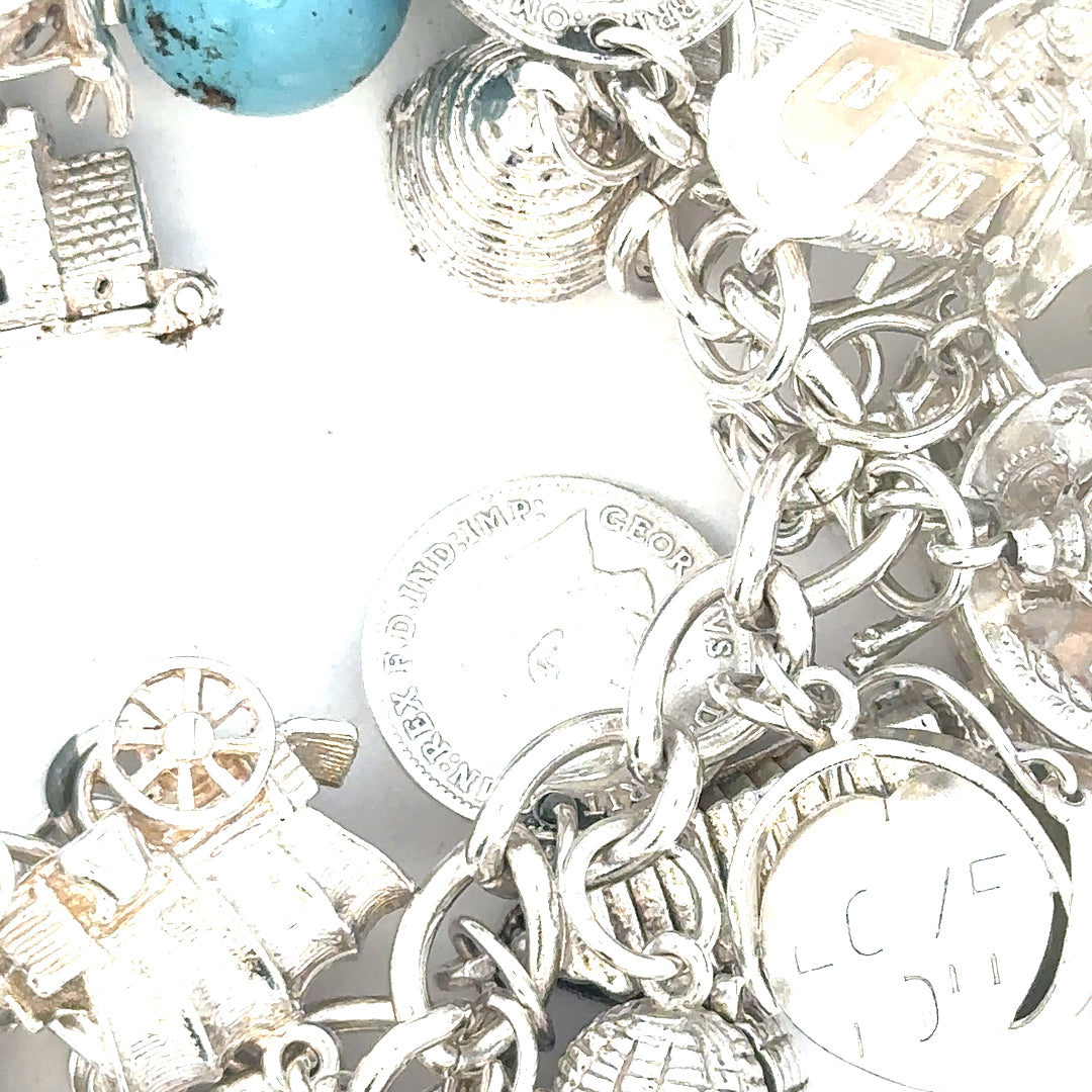 Silver charm bracelet featuring intricate designs, weighing 128.8g, with detailed charms and links, unbranded fashion jewelry.