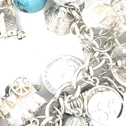 Silver charm bracelet featuring intricate designs, weighing 128.8g, with detailed charms and links, unbranded fashion jewelry.