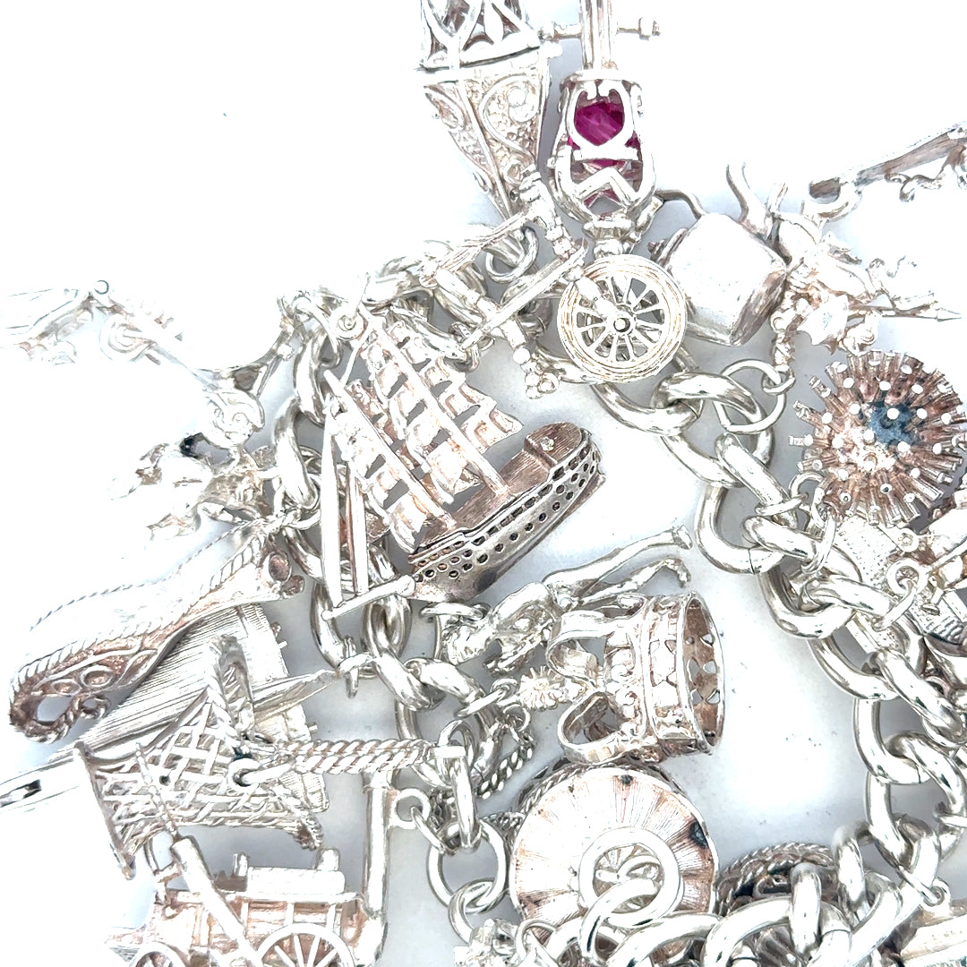 Silver charm bracelet with intricate designs, weighing 154.4g, featuring multiple charms and a secure clasp.