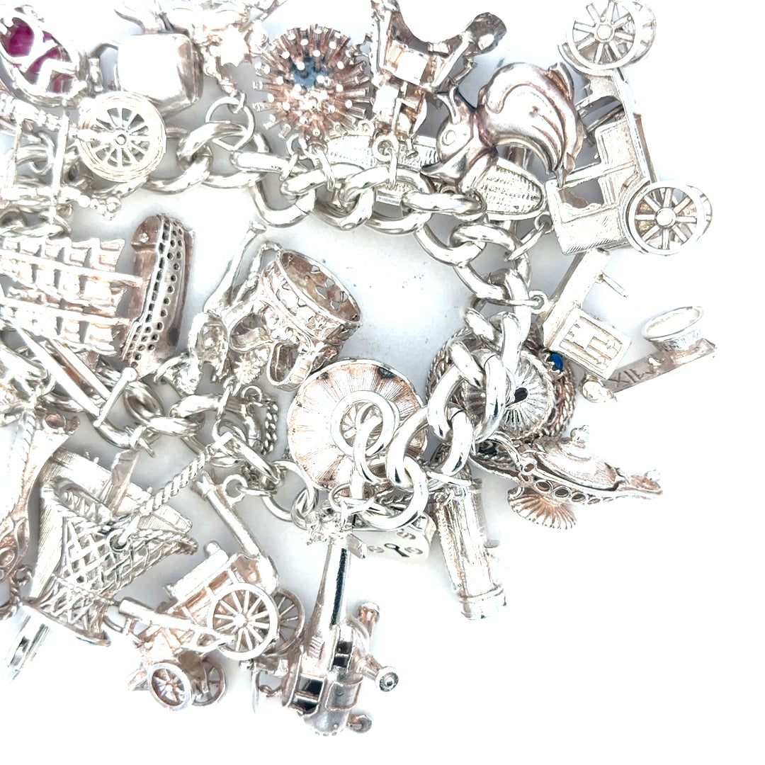 Silver charm bracelet weighing 154.4g with intricate charms, unbranded, showcasing detailed design and polished finish.