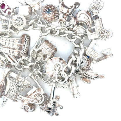Silver charm bracelet weighing 154.4g with intricate charms, unbranded, showcasing detailed design and polished finish.
