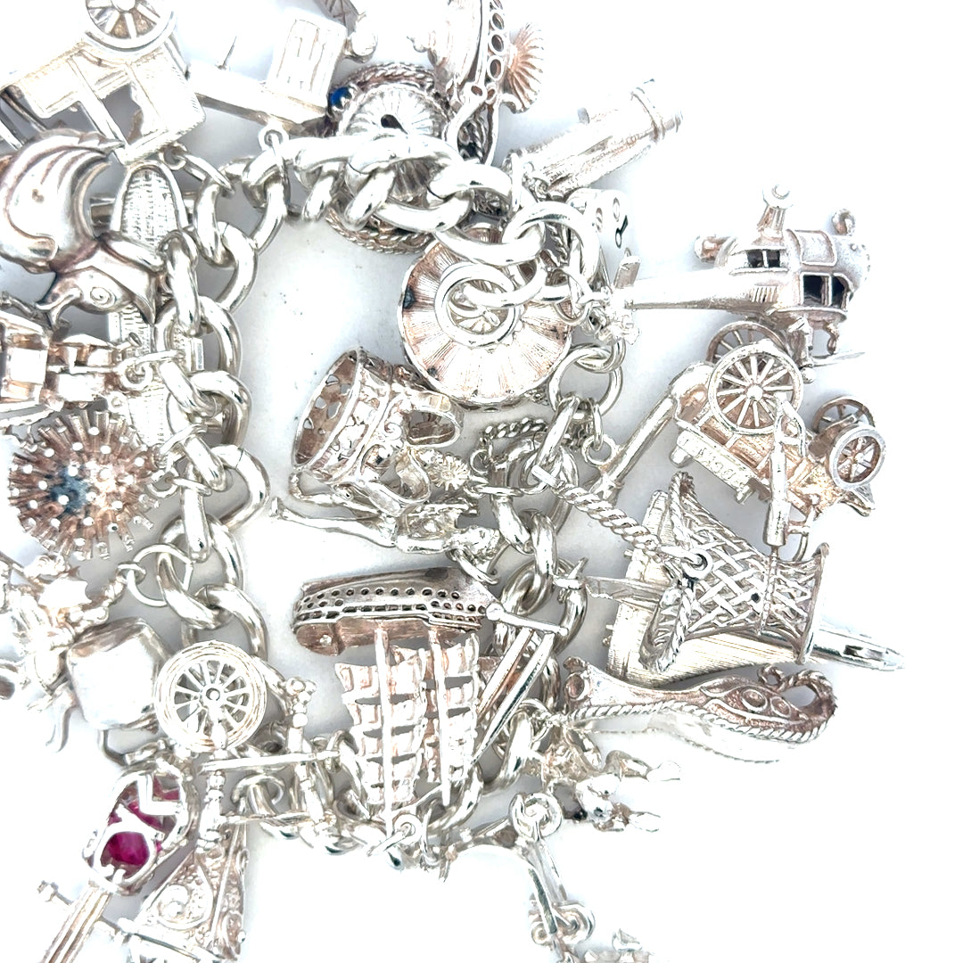 Silver charm bracelet weighing 154.4g, featuring various decorative charms, unbranded jewelry accessory.
