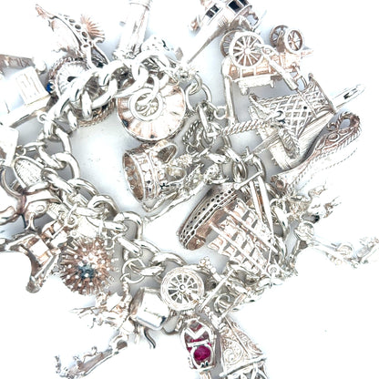 Silver charm bracelet weighing 154.4g, featuring multiple decorative charms and a secure clasp, unbranded jewelry accessory.