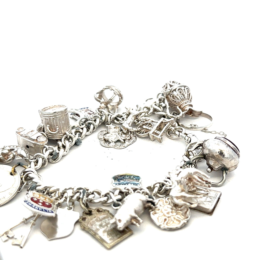 Silver charm bracelet weighing 61g with intricate charms, unbranded, showcased on a neutral background.