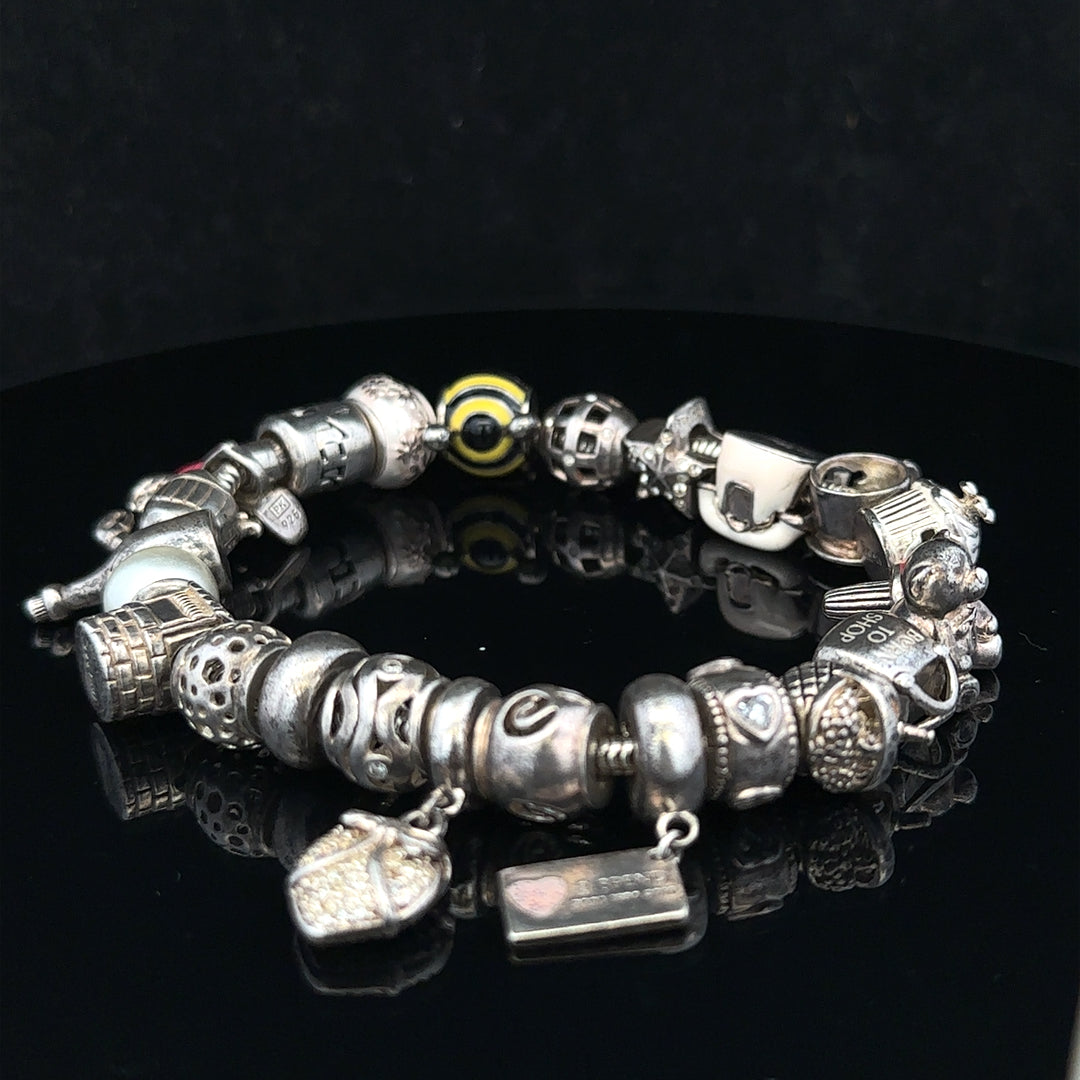 Silver charm bracelet with intricate designs, featuring multiple charms on a classic bracelet style.