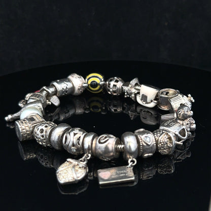 Silver charm bracelet with intricate designs, featuring multiple charms on a classic bracelet style.