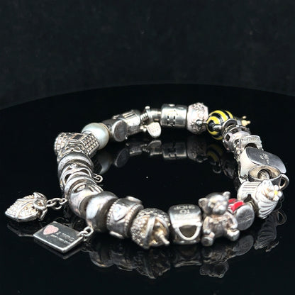 Silver charm bracelet with intricate charms, unbranded, size 64.8, featuring detailed metalwork and adjustable clasp.