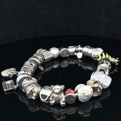 Silver charm bracelet with intricate detailing, featuring various charms, designed for stylish wear and everyday elegance.