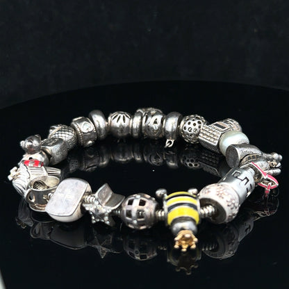 Silver charm bracelet with various decorative charms, unbranded, 64.8 cm length, showing intricate details and shiny silver finish.