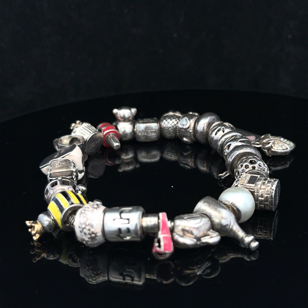 Silver charm bracelet with intricate designs, featuring multiple charms on a sleek chain, 64.8 cm length, unbranded jewelry accessory.