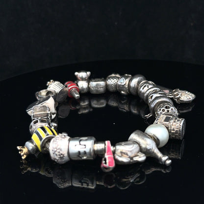 Silver charm bracelet with intricate designs, featuring multiple charms on a sleek chain, 64.8 cm length, unbranded jewelry accessory.