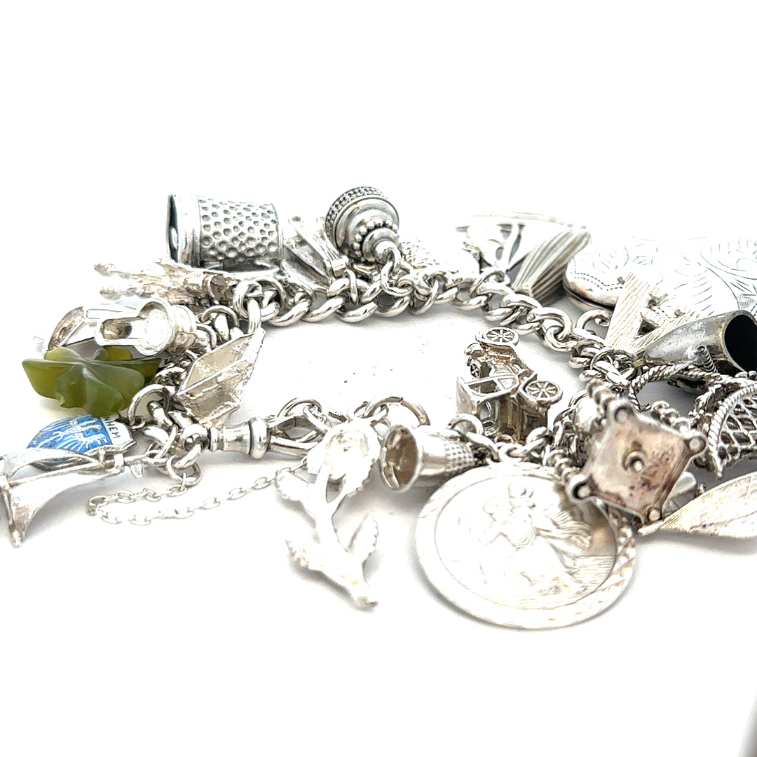 Silver charm bracelet weighing 83.4g with various decorative charms, unbranded jewelry accessory on a neutral background.