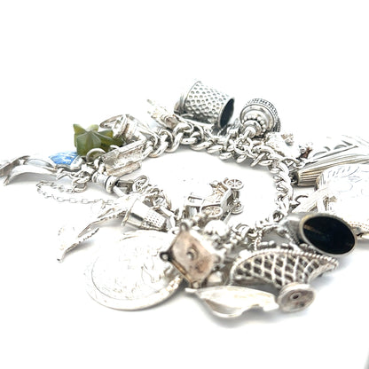 Silver charm bracelet with intricate details, weighs 83.4g, featuring multiple charms and a secure clasp.