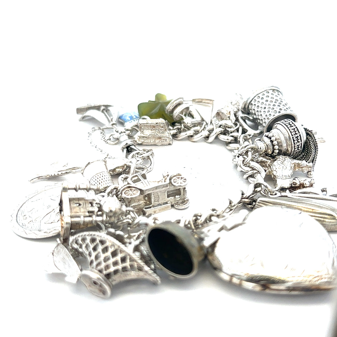 Silver charm bracelet weighing 83.4g with decorative charms, unbranded, featuring intricate metalwork and a secure clasp.