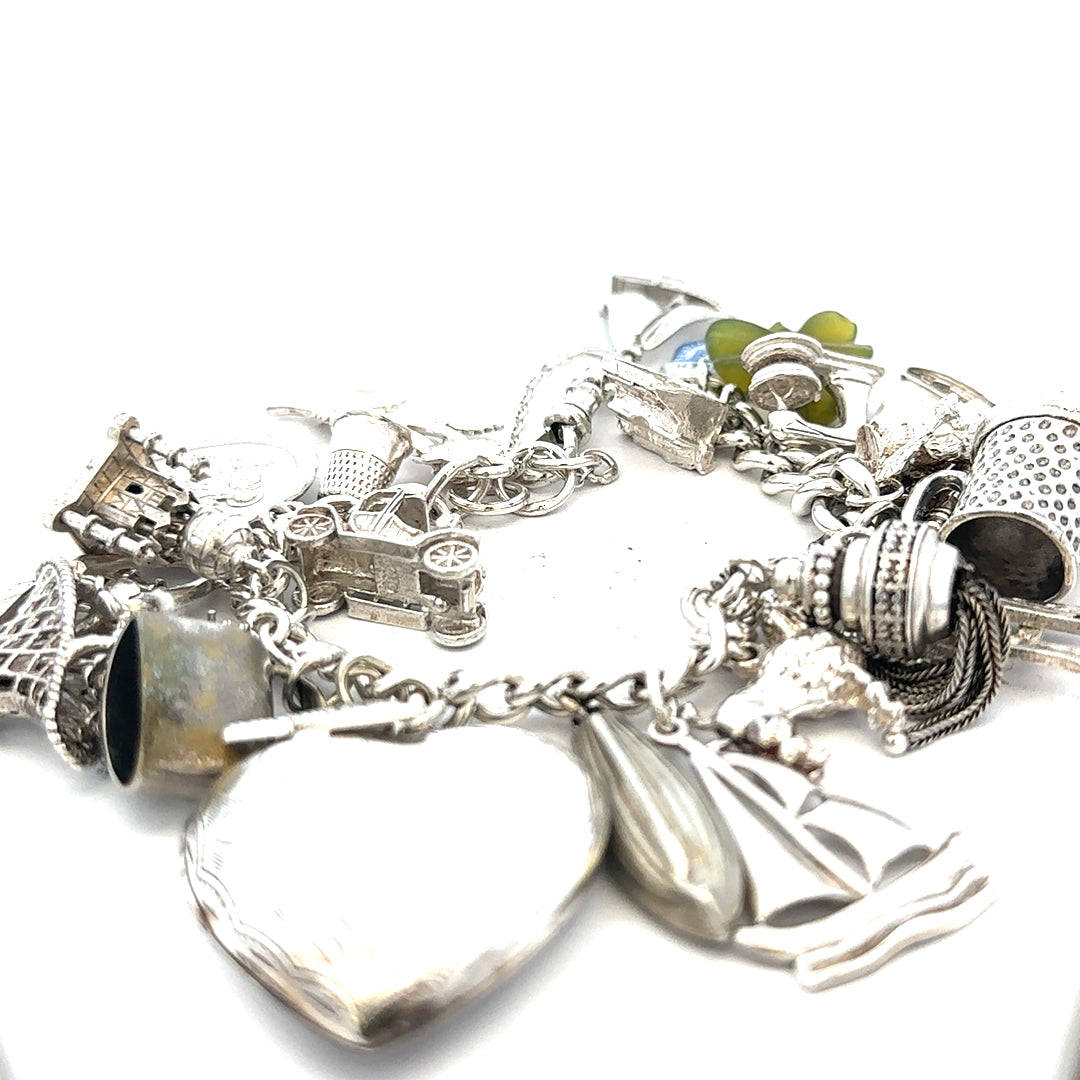 Silver charm bracelet weighing 83.4g with intricate charms, crafted from unbranded silver, displayed on a neutral background.