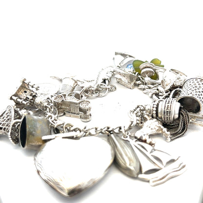 Silver charm bracelet weighing 83.4g with intricate charms, crafted from unbranded silver, displayed on a neutral background.