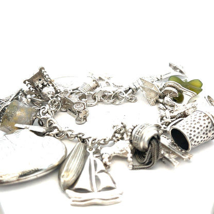 Silver charm bracelet with intricate designs, weighing 83.4g, featuring various charms and a secure clasp.