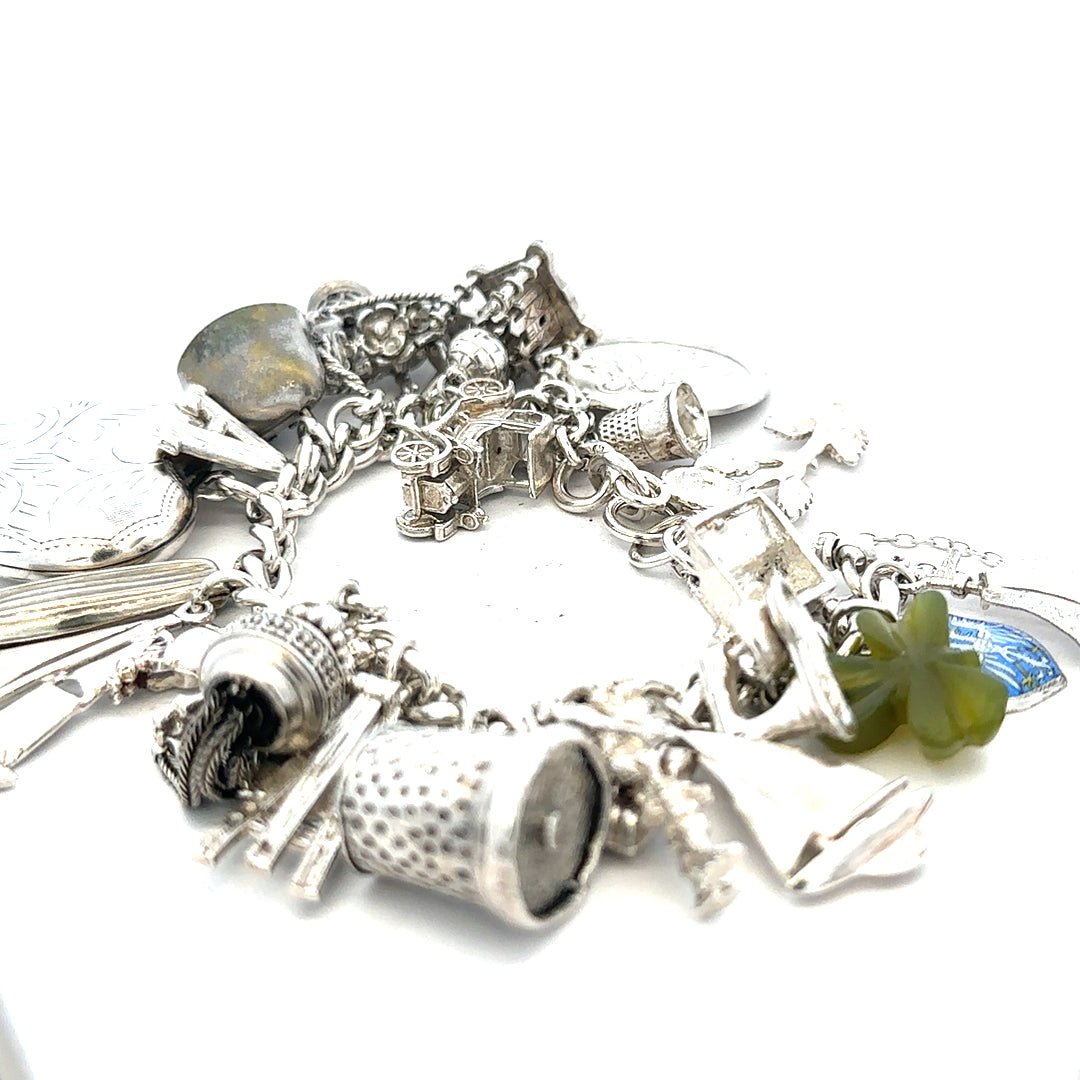 Silver charm bracelet with intricate details, weighing 83.4g, featuring various decorative charms on a classic bracelet style.