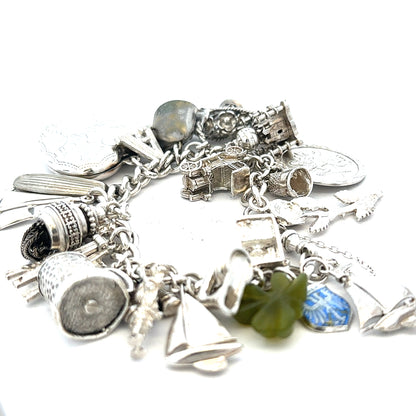 Silver charm bracelet weighing 83.4g with multiple charms, unbranded jewelry accessory, displayed on a neutral background.