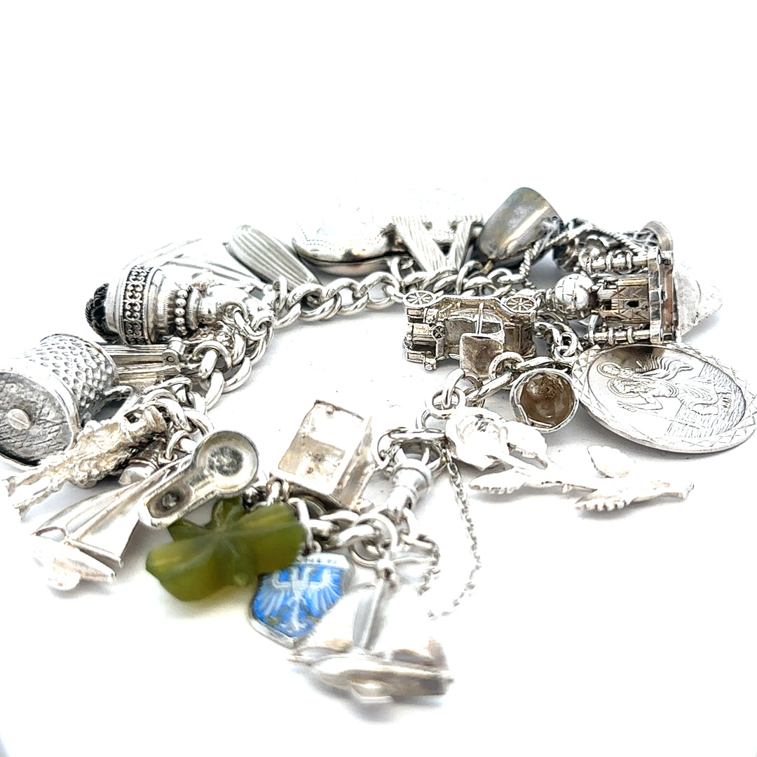 Silver charm bracelet with intricate designs, weighing 83.4g, featuring multiple decorative charms and a secure clasp.