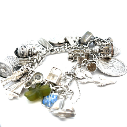 Silver charm bracelet with intricate designs, weighing 83.4g, featuring multiple decorative charms and a secure clasp.