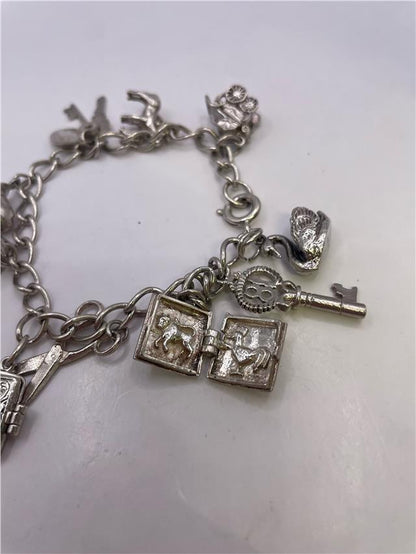 Silver charm bracelet with intricate designs, weighing 33.9 grams, featuring various decorative charms on a classic chain.