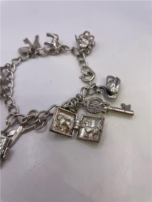 Silver charm bracelet with intricate designs, weighing 33.9 grams, featuring various decorative charms on a classic chain.