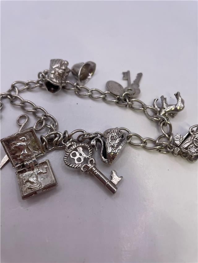 Silver charm bracelet with intricate designs, weighing 33.9g, featuring various decorative charms on a classic bracelet style.