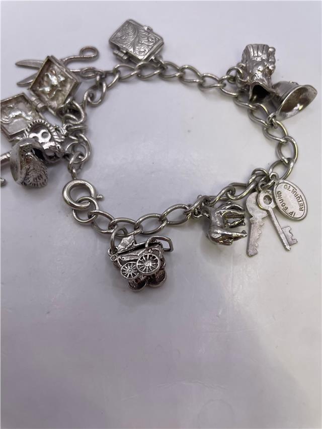 Silver charm bracelet weighing 33.9g with multiple charms, featuring a stylish unbranded bracelet design.