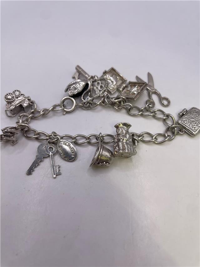 Silver charm bracelet weighing 33.9g with decorative charms, featuring a stylish unbranded bracelet design.