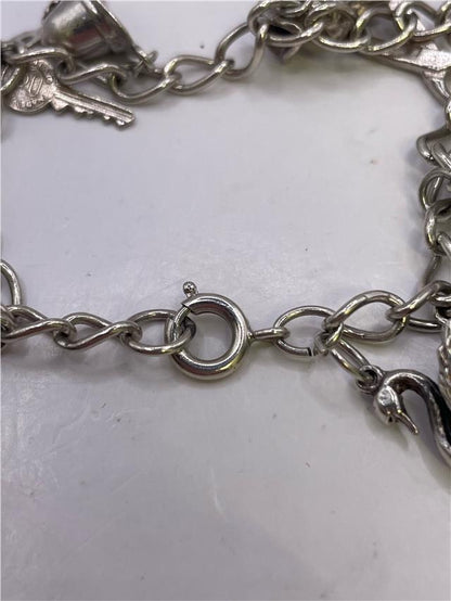 Silver charm bracelet with intricate designs, weighing 33.9g, crafted for stylish wear and versatile accessorizing.