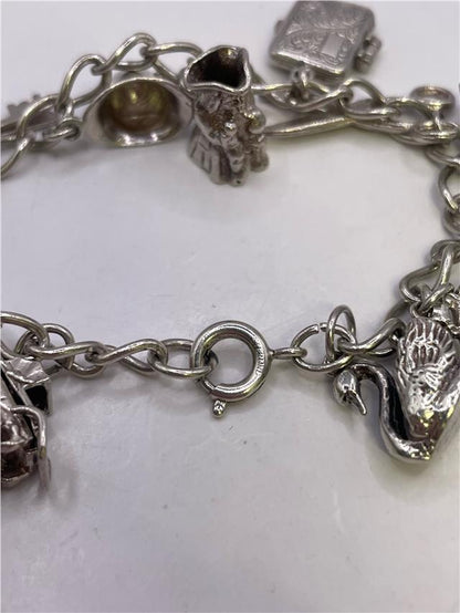 Silver charm bracelet with intricate designs, weighing 33.9g, featuring various decorative charms on a sleek bracelet.