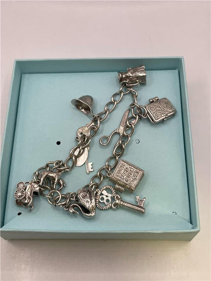 Silver charm bracelet with intricate designs, weighing 33.9g, featuring various decorative charms in a stylish unbranded bracelet.